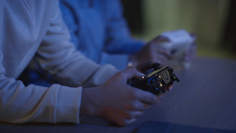 Close-Up-Of-Two-Young-Boys-At-Home-Playing-With-Computer-Games-Console-On-TV-Holding-Controllers-Late-At-Night-2